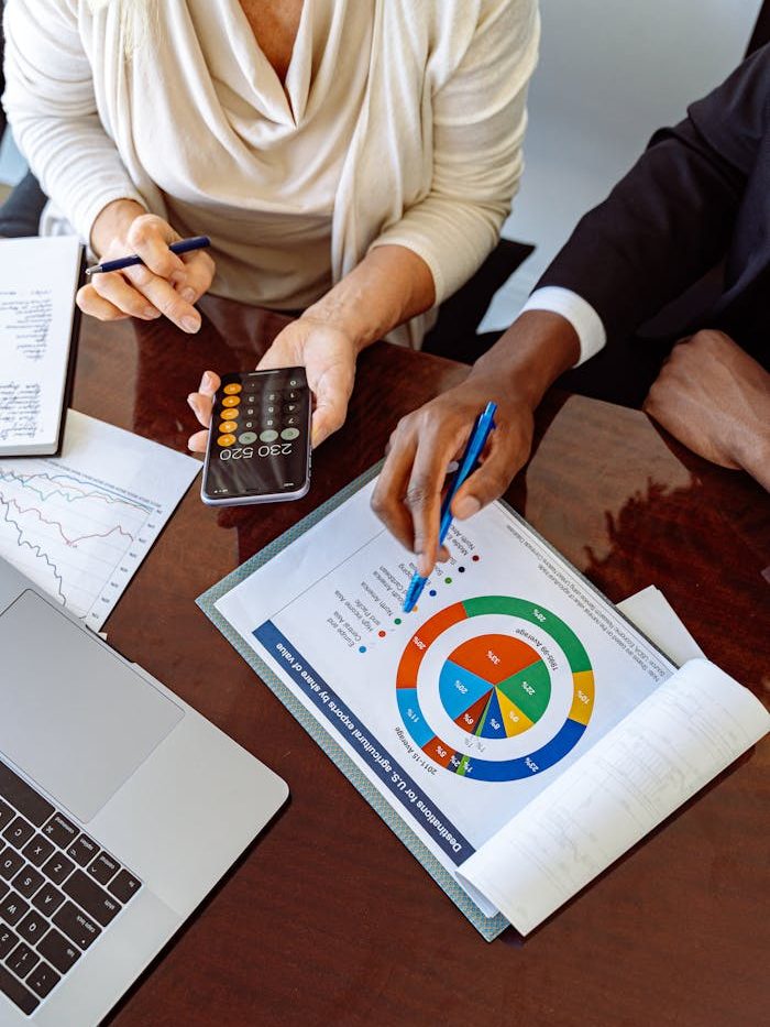 Two business professionals discussing financial documents and strategies at an office desk.
